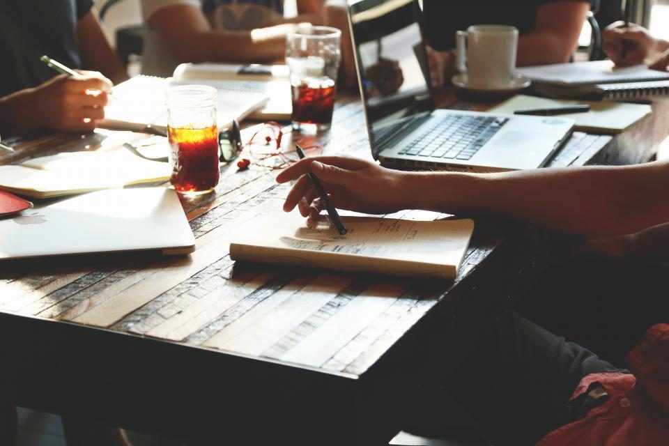 Wspólna praca nad wdrożeniem: notatki, laptopy i rozpisany przebieg zadania na stole.